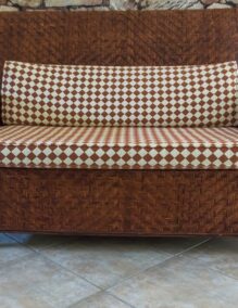 A large golden wicker sofa with chequered cushions