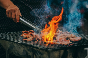 Bacon grilling on a flaming BBQ